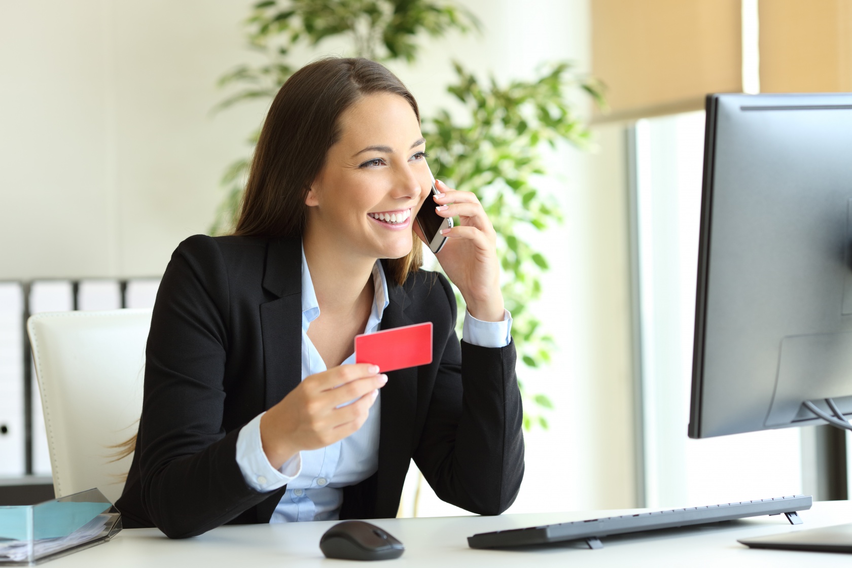 Office lady smiling while making payment over the phone